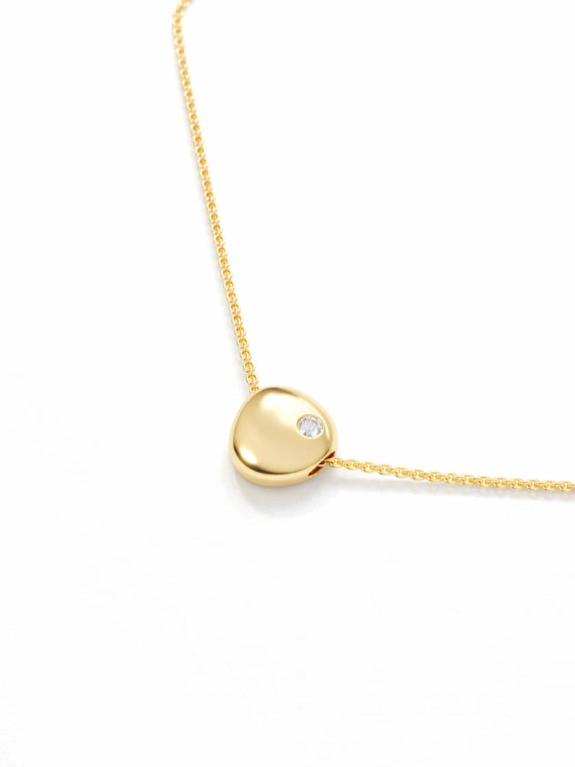 Gold necklace with a heart-shaped pendant on a white background