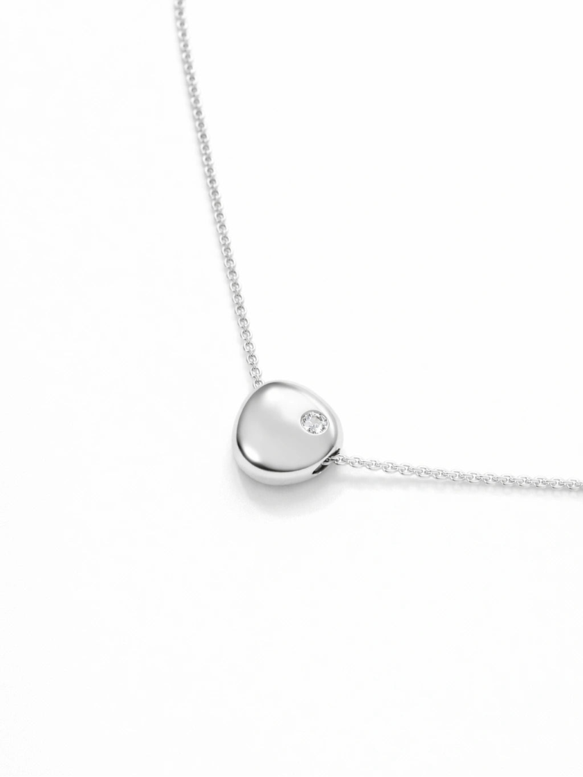 Silver necklace with a heart-shaped pendant on a white background