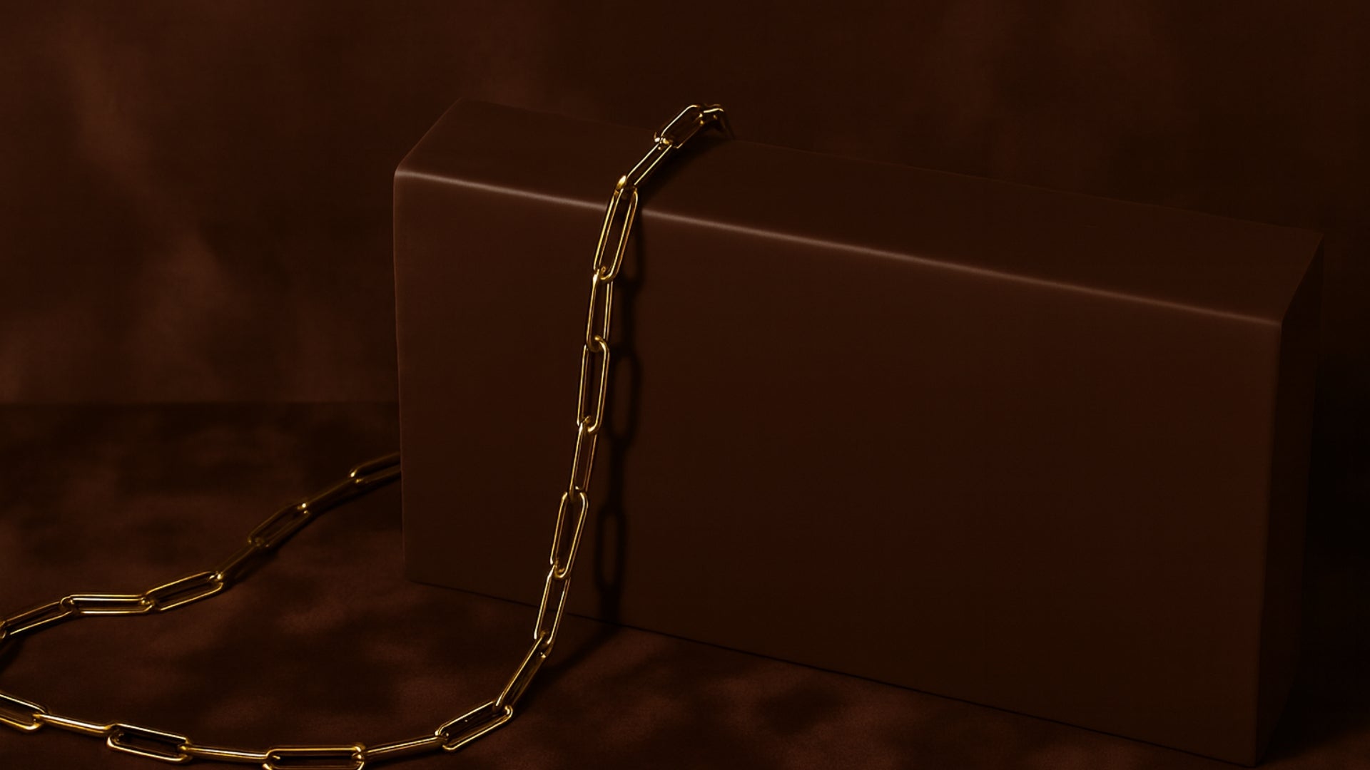 Gold chain draped over a brown box on a dark background