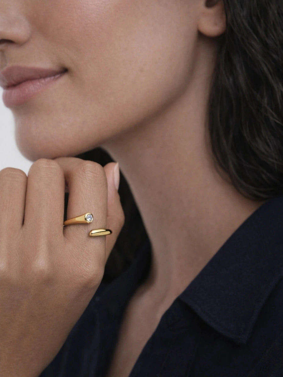 Close-up of a woman's face wearing two gold rings on her fingers.